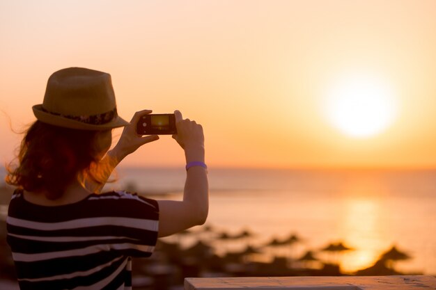 Joven, mujer, toma, imagen, mar, salida del sol