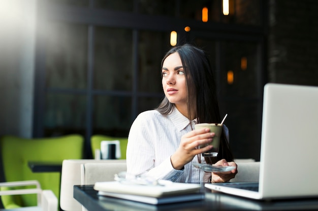 Foto gratuita joven mujer tomando un café mientras estudiaba