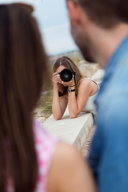 Joven mujer tomando fotos de una pareja en la ciudad.