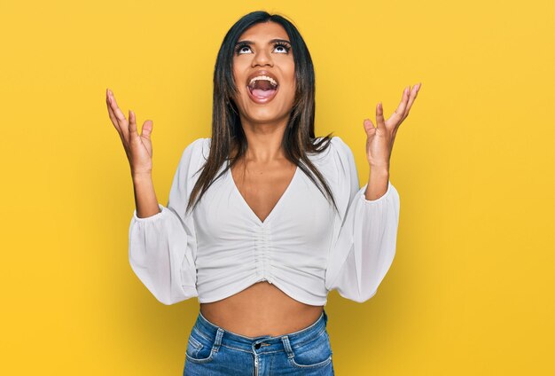 Joven mujer transgénero transexual latina con ropa casual loca y loca gritando y gritando con expresión agresiva y concepto de frustración con los brazos levantados