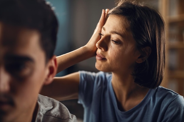 Joven mujer triste limpiándose las lágrimas mientras tiene problemas en una relación con su novio