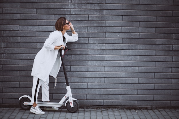 Foto gratuita joven mujer vestida de blanco scooter