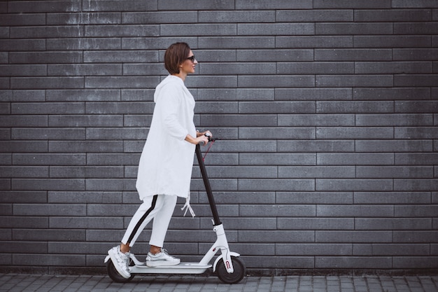 Joven mujer vestida de blanco scooter