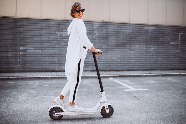 Joven mujer vestida de blanco scooter