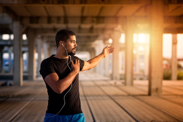 Joven musculoso estirando y preparándose para el entrenamiento físico