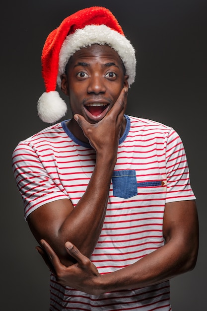 Joven musculoso sorprendido con sombrero de Santa Claus