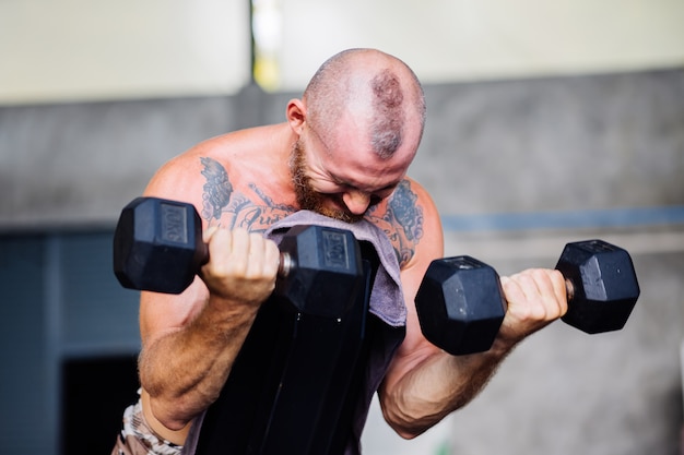 Joven musculoso tatuado fuerte músculo barbudo hombre europeo haciendo ejercicio duro