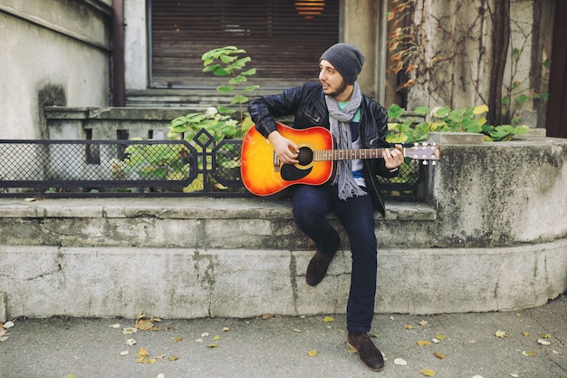 Joven músico con guitarra en la ciudad