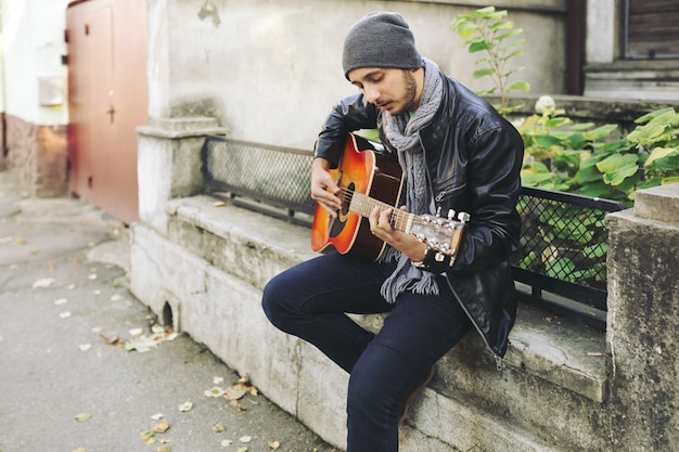 Joven músico con guitarra en la ciudad