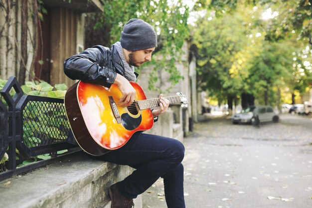 Joven músico con guitarra en la ciudad
