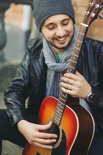 Joven músico con guitarra en la ciudad