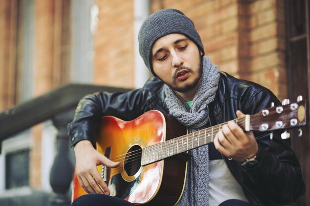 Joven músico con guitarra en la ciudad