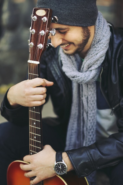 Joven músico con guitarra en la ciudad