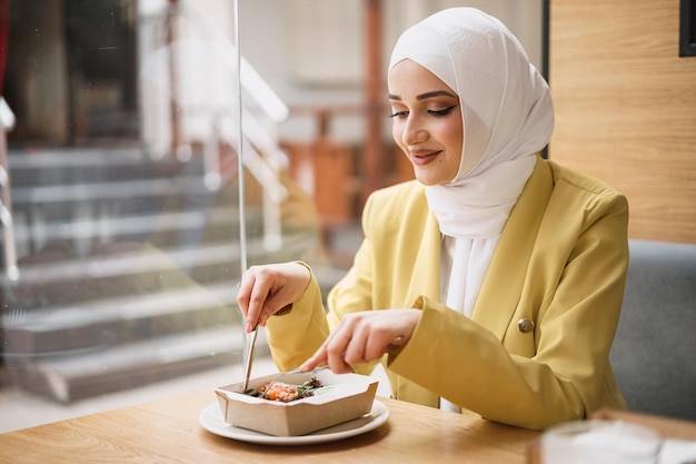 Joven musulmana en hijab almorzando en el café