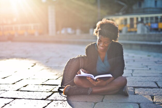 joven negra en la calle lee un libro