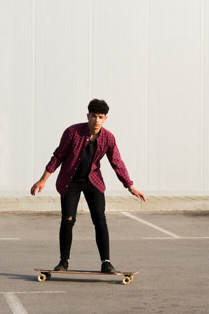 Joven negro en denim negro montando patineta