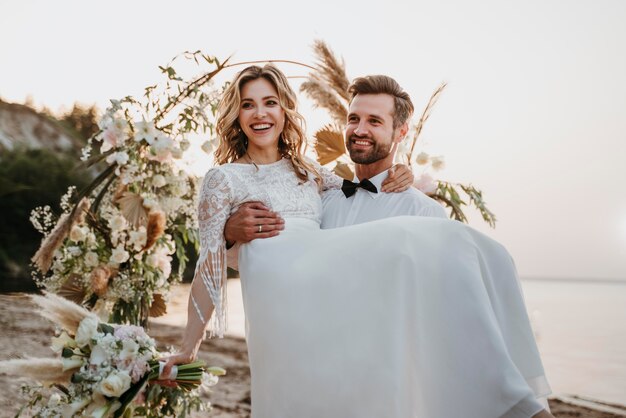 La joven novia y el novio con una boda en la playa