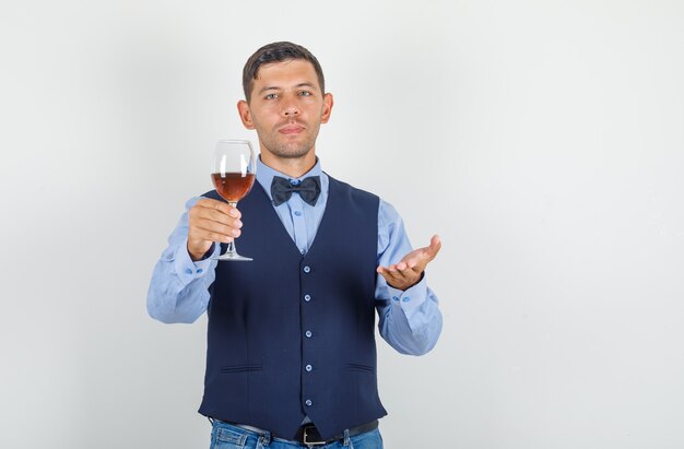 Joven ofreciendo bebida alcohólica en traje, jeans