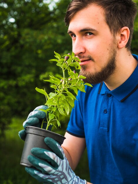 Joven oliendo la planta en maceta