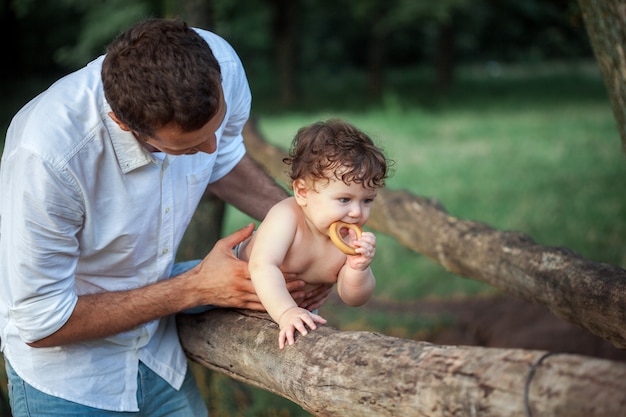 Joven padre hermoso y pequeño hijo del niño contra la hierba verde