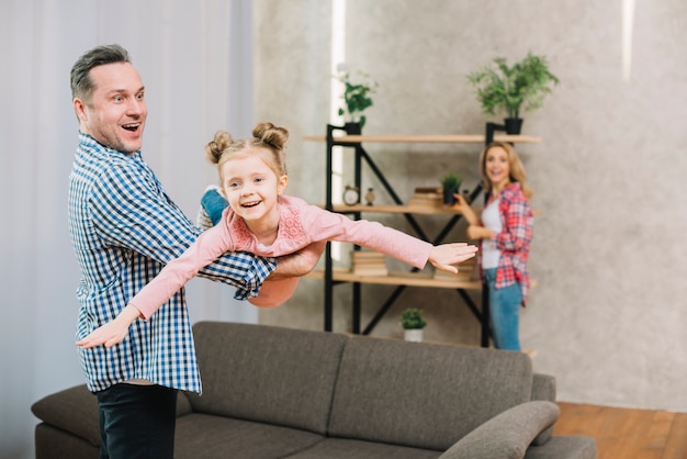 Foto gratuita joven padre llevando a su hija en la sala