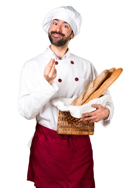 Joven panadero sosteniendo un poco de pan y haciendo gesto de dinero