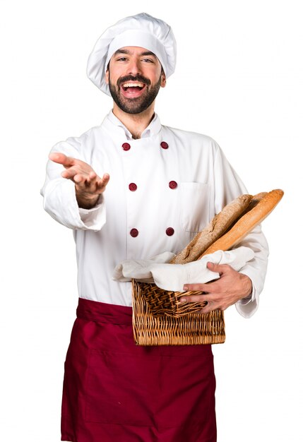 Joven panadero sosteniendo un poco de pan y presentando algo