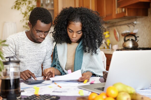 Joven pareja afroamericana gestionando las finanzas juntos en casa