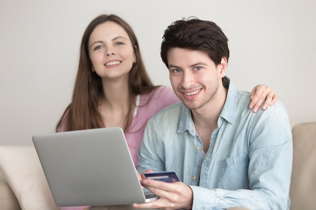 Joven pareja alegre de compras en línea a través del ordenador portátil