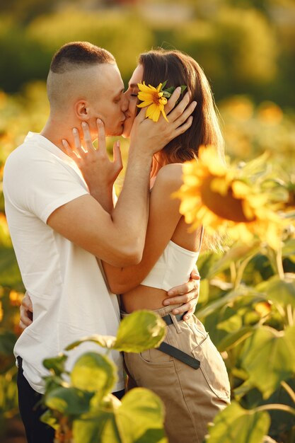 Joven pareja amorosa se besa en un campo de girasoles. Retrato de pareja posando en verano en campo.