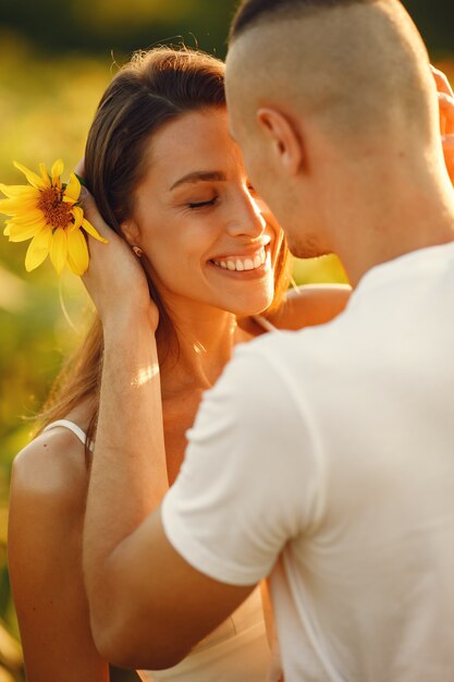 Joven pareja amorosa se besa en un campo de girasoles. Retrato de pareja posando en verano en campo.