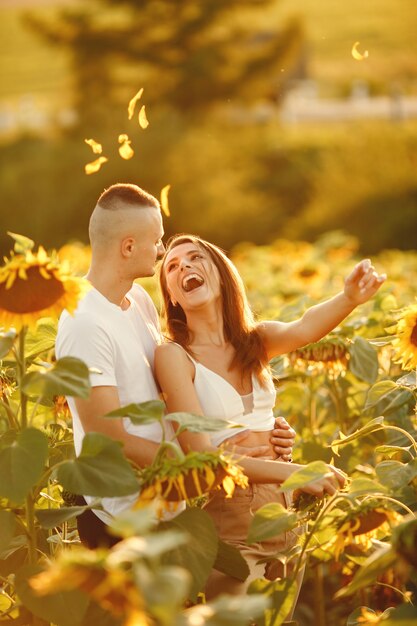 Joven pareja amorosa se besa en un campo de girasoles. Retrato de pareja posando en verano en campo.