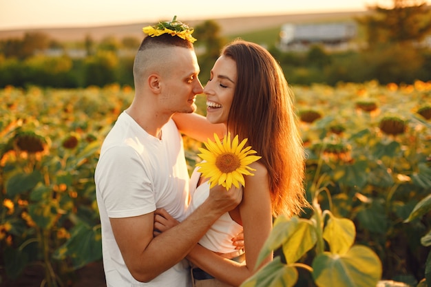 Joven pareja amorosa se besa en un campo de girasoles. Retrato de pareja posando en verano en campo.