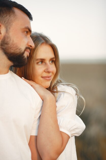 Joven pareja amorosa se besa en un campo de girasoles. Retrato de pareja posando en verano en campo.