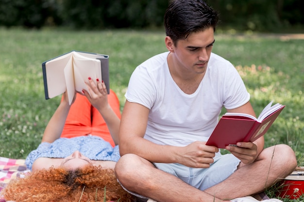 Joven pareja amorosa leyendo libros al aire libre