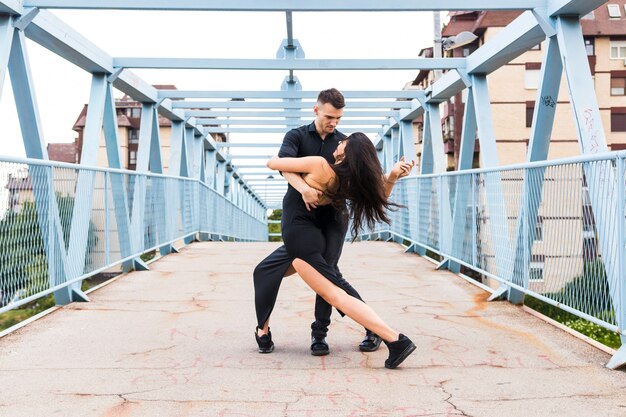 Joven pareja bailando tango sobre el puente