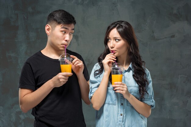 Una joven pareja bastante asiática con unas copas de jugo de naranja