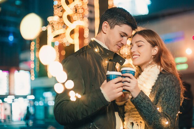Joven pareja besándose y abrazándose al aire libre en la calle de noche en Navidad