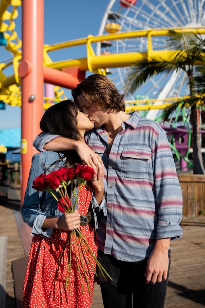 Joven pareja besándose en una cita en el parque de diversiones