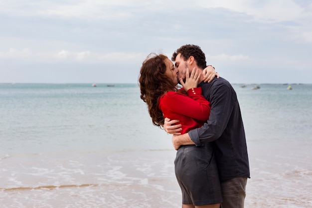 Joven pareja besándose en la orilla del mar de arena