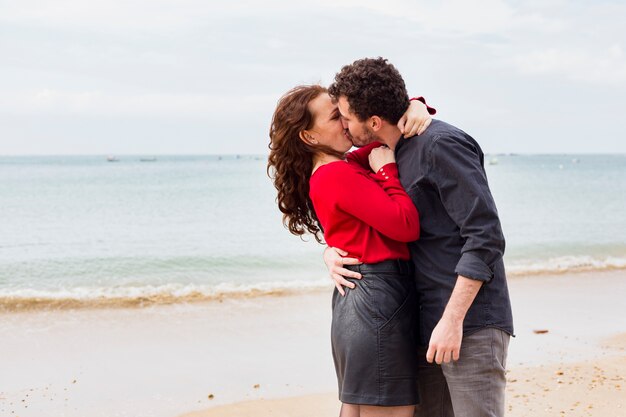 Joven pareja besándose en la orilla del mar