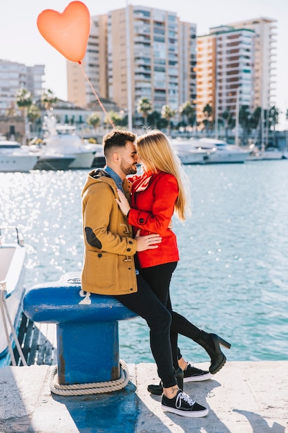 Foto gratuita joven pareja besándose en el paseo marítimo