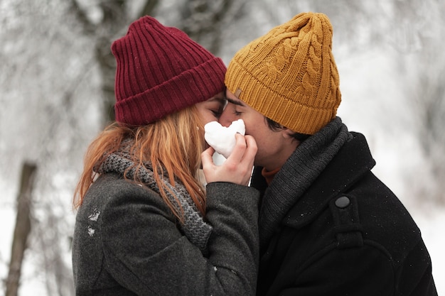 Joven pareja besándose en la temporada de invierno tiro medio