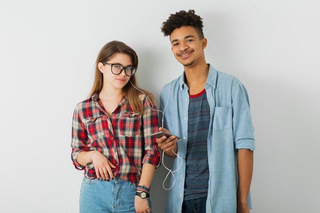 Joven pareja bonita, guapo negro, hermosa chica, gafas, aislado, juventud, estilo hipster, estudiantes, amigos juntos, sonriendo feliz, sosteniendo smartphone, escuchando música en auriculares