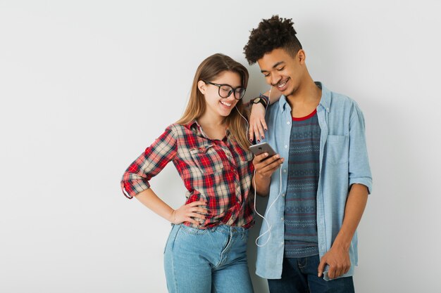 Joven pareja bonita, guapo negro, hermosa chica, gafas, aislado, juventud, estilo hipster, estudiantes, amigos juntos, sonriendo feliz, sosteniendo smartphone, escuchando música en auriculares