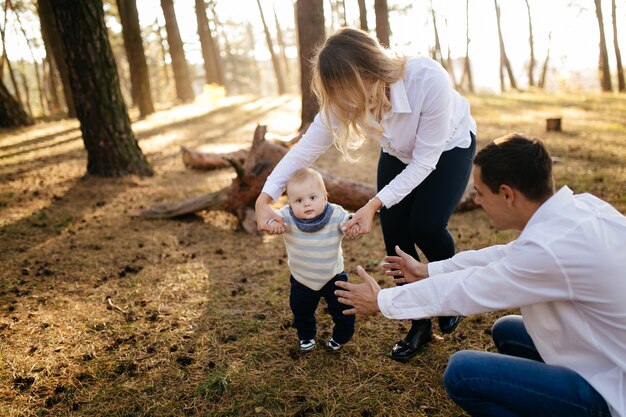 Foto gratuita una joven pareja camina en el bosque con un niño pequeño