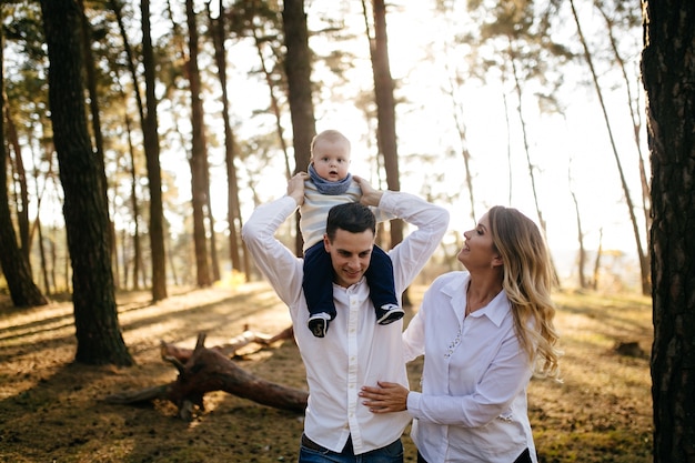 Foto gratuita una joven pareja camina en el bosque con un niño pequeño