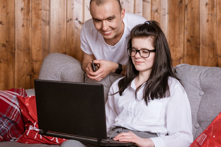 Foto gratuito una joven pareja en casa sentada en el sofá comunicándose en línea a través de una computadora portátil con familiares