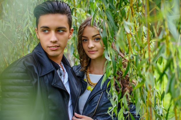 Joven pareja casual de hombres y mujeres bajo un árbol verde.