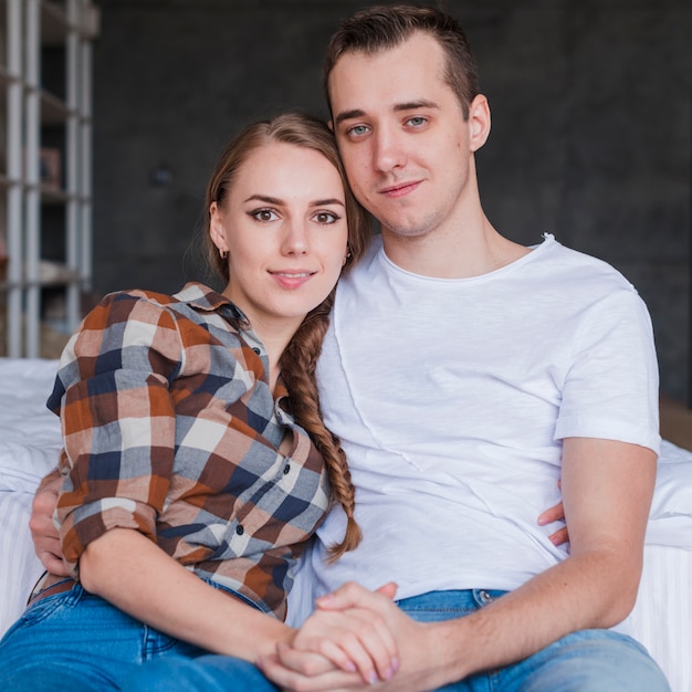 Foto gratuita joven pareja contenta abrazando cerca de la cama en su casa